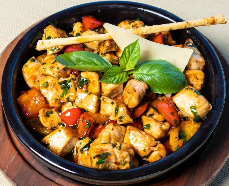 Golden chicken breasts searing evenly in a stainless skillet with olive oil and aromatics